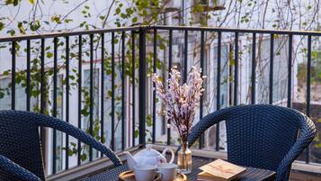 A balcony with wicker furniture, a teapot, a cup, and a vase with flowers.