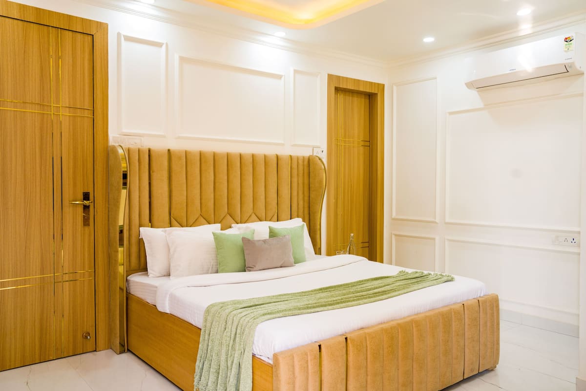 Een slaapkamer met een houten bedframe, witte beddengoed en een groene plaid.
