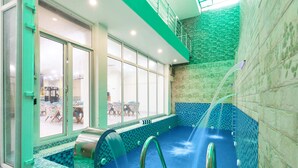 Une piscine intérieure dotée d’un mur en verre donnant sur un espace extérieur.