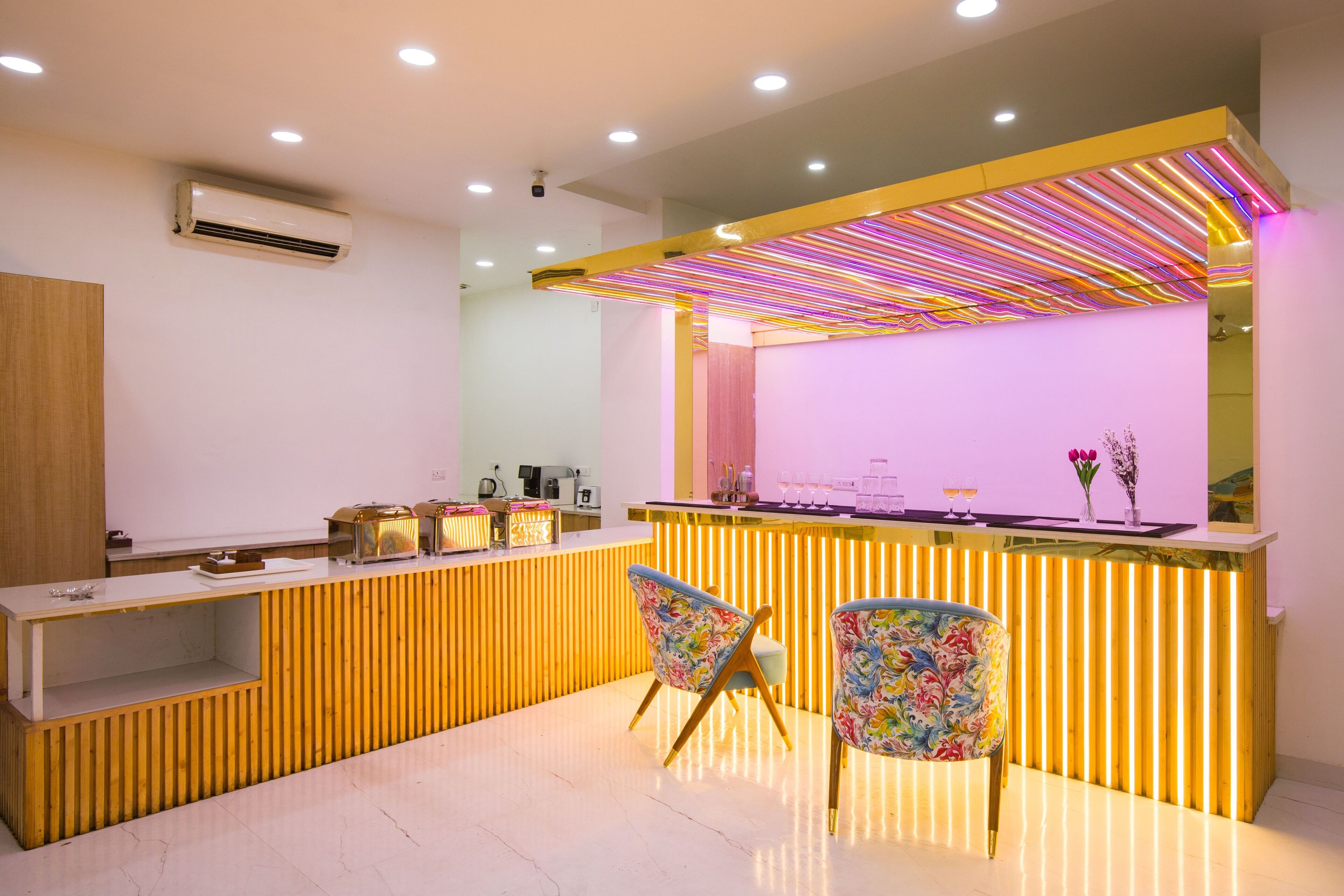 A reception area with a wooden counter, two floral chairs, and a neon-lit ceiling.