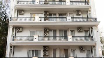 A multi-story building with balconies, air conditioning units, and a gated entrance.