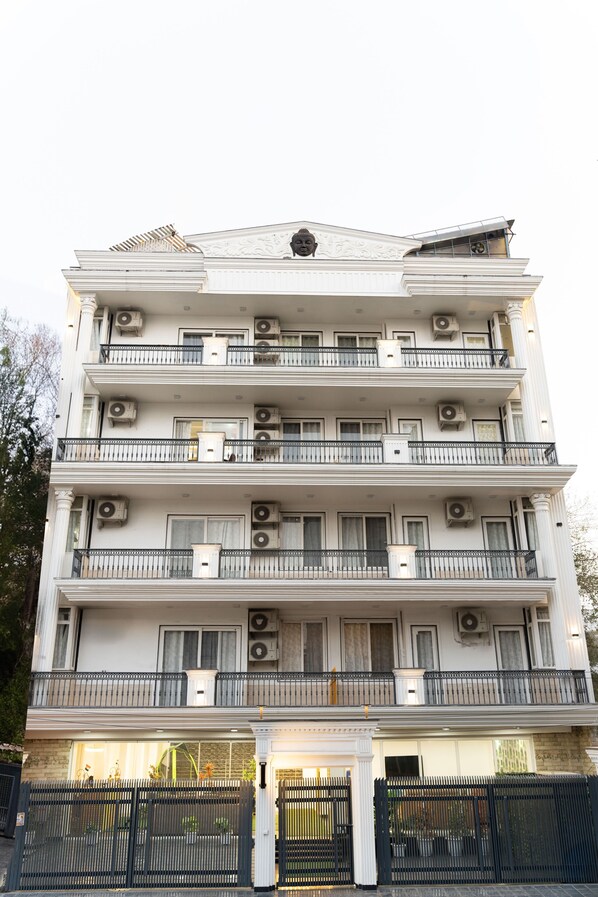 A multi-story building with balconies, air conditioning units, and a gated entrance. - Alaya Stays Miyabi Executive Suite, Elegant 1-BHK Suite With Common Pool, Gym & Restaurant (Gurugram)