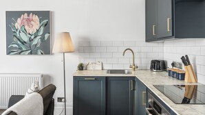 A modern kitchen with dark cabinets, a marble countertop, a sink, and a toaster.