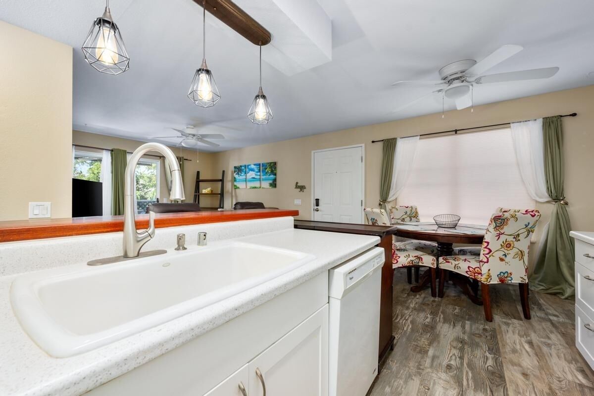 A kitchen with a large sink, wooden countertop, and a dining area with a table and chairs.