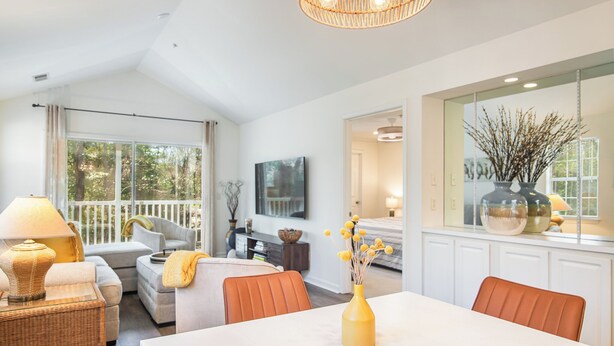 A modern living room with a dining area, large windows, and a view of the outdoors.