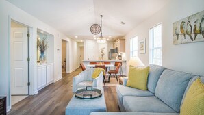 A spacious living room with a grey sofa, a coffee table, and a dining area in the background.