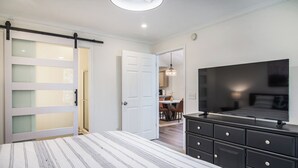 A bedroom with a bed, a TV, a dresser, and a sliding door.