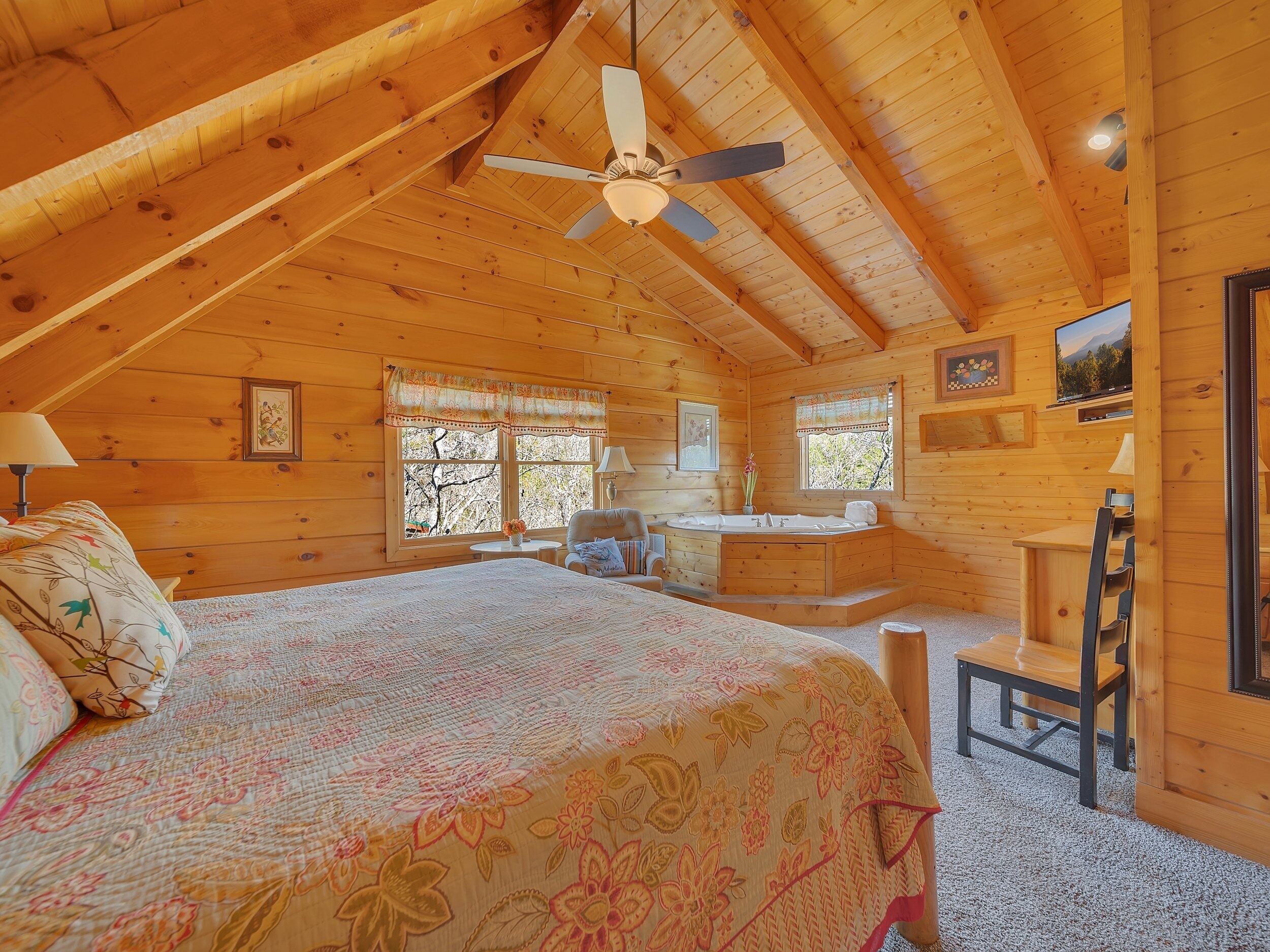 A cozy cabin with a large bed, a desk, and a bathroom.