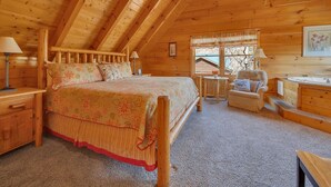 Un dormitorio acogedor tipo cabaña de madera con cama, una silla, tocador y ventilador de techo.