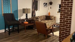 A living room with a patterned sofa, two armchairs, a coffee table, and a lamp.