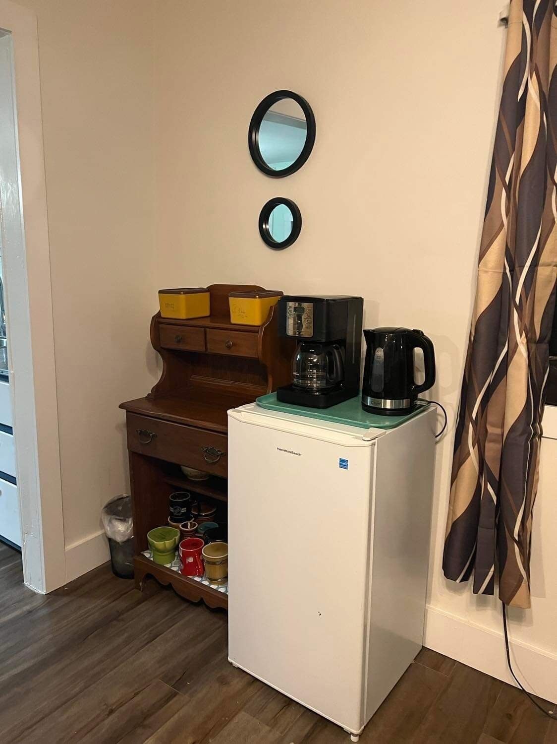 Eine kleine Küchenzeile mit einem kleinen Kühlschrank, einer Kaffeemaschine und einer Mikrowelle.