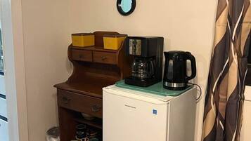 Eine kleine Küchenzeile mit einem kleinen Kühlschrank, einer Kaffeemaschine und einer Mikrowelle.