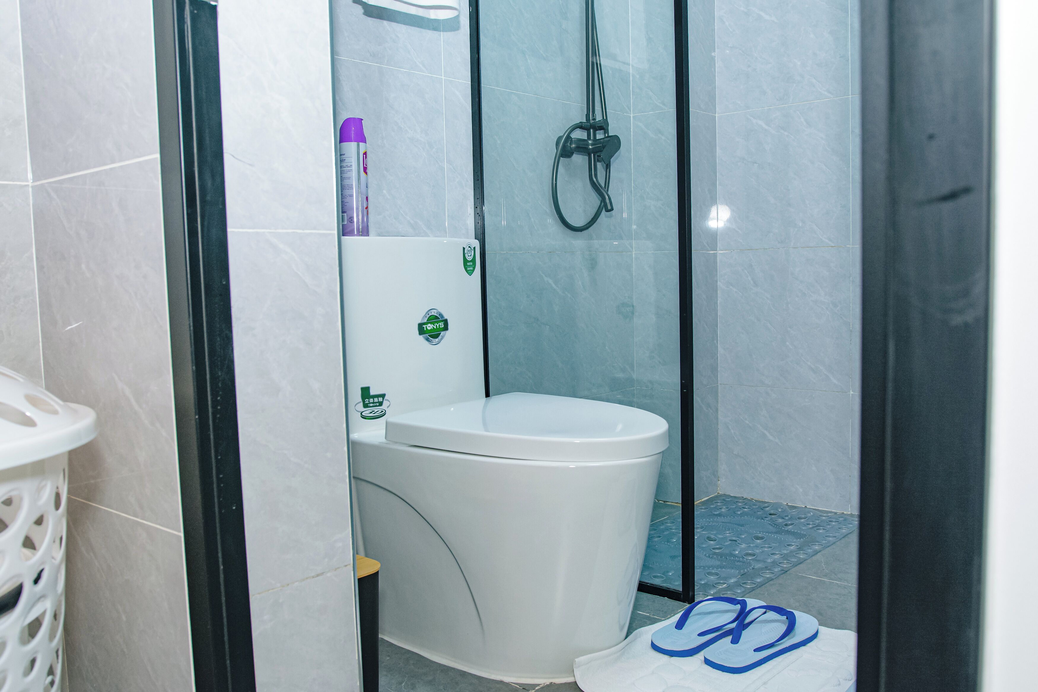 A bathroom with a toilet, a shower, and a tiled floor.
