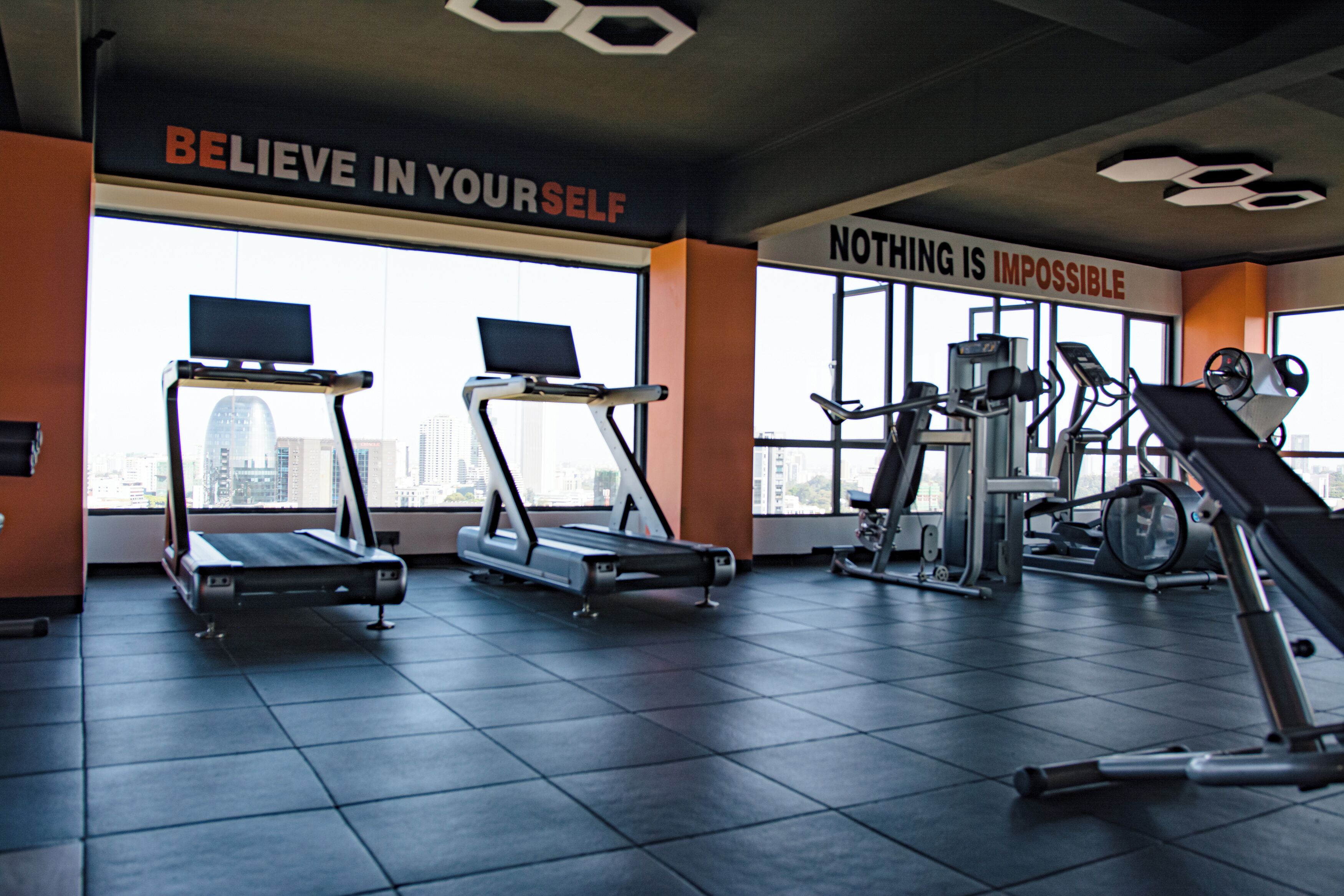 Une salle de sport équipée de tapis de course, d’appareils de musculation et de posters motivants.