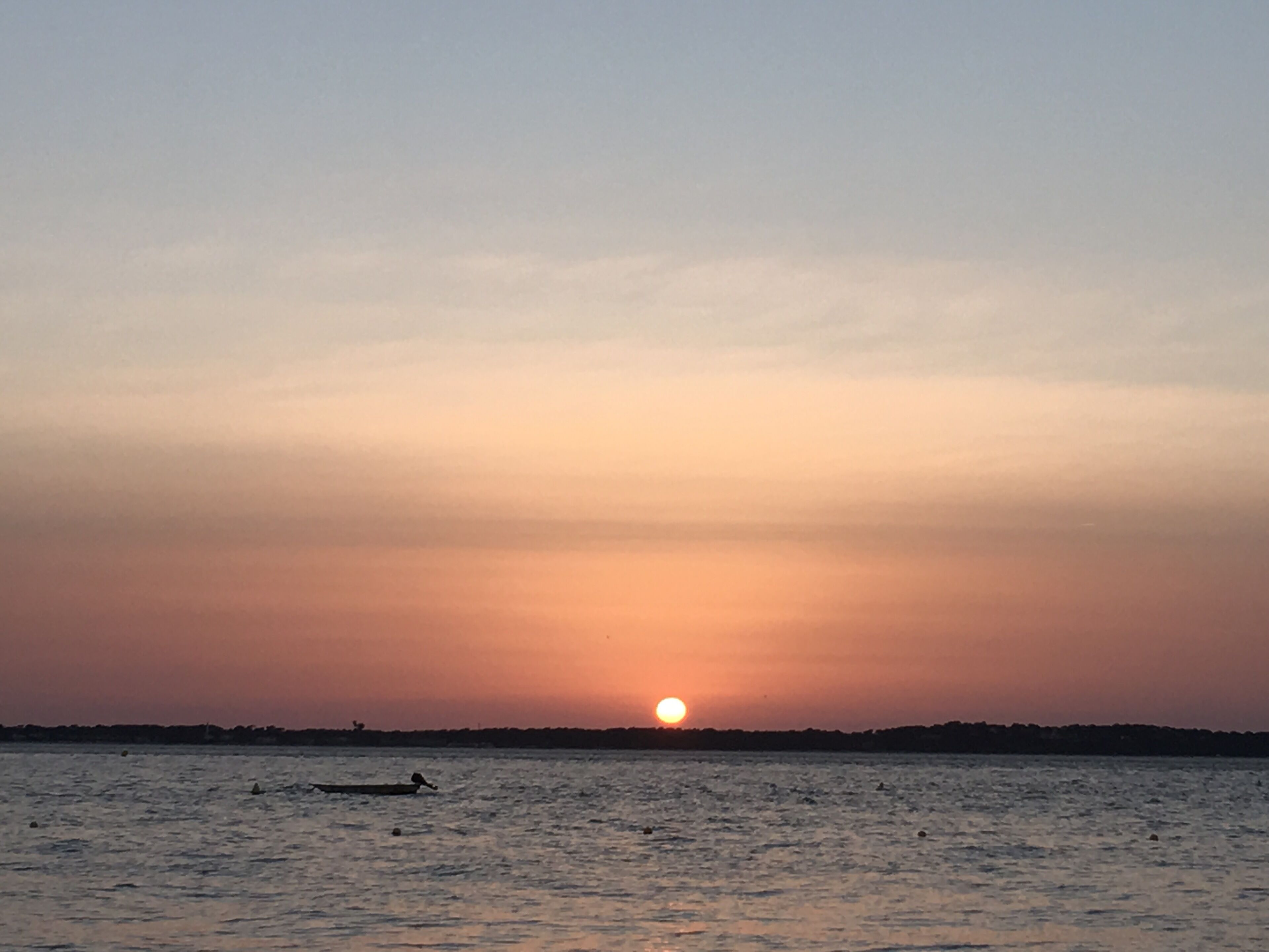Un tramonto su acque calme con una barca in primo piano.