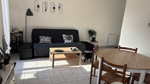 Ett modernt vardagsrum med en soffa, ett soffbord, ett matbord, stolar och en krukväxt.
