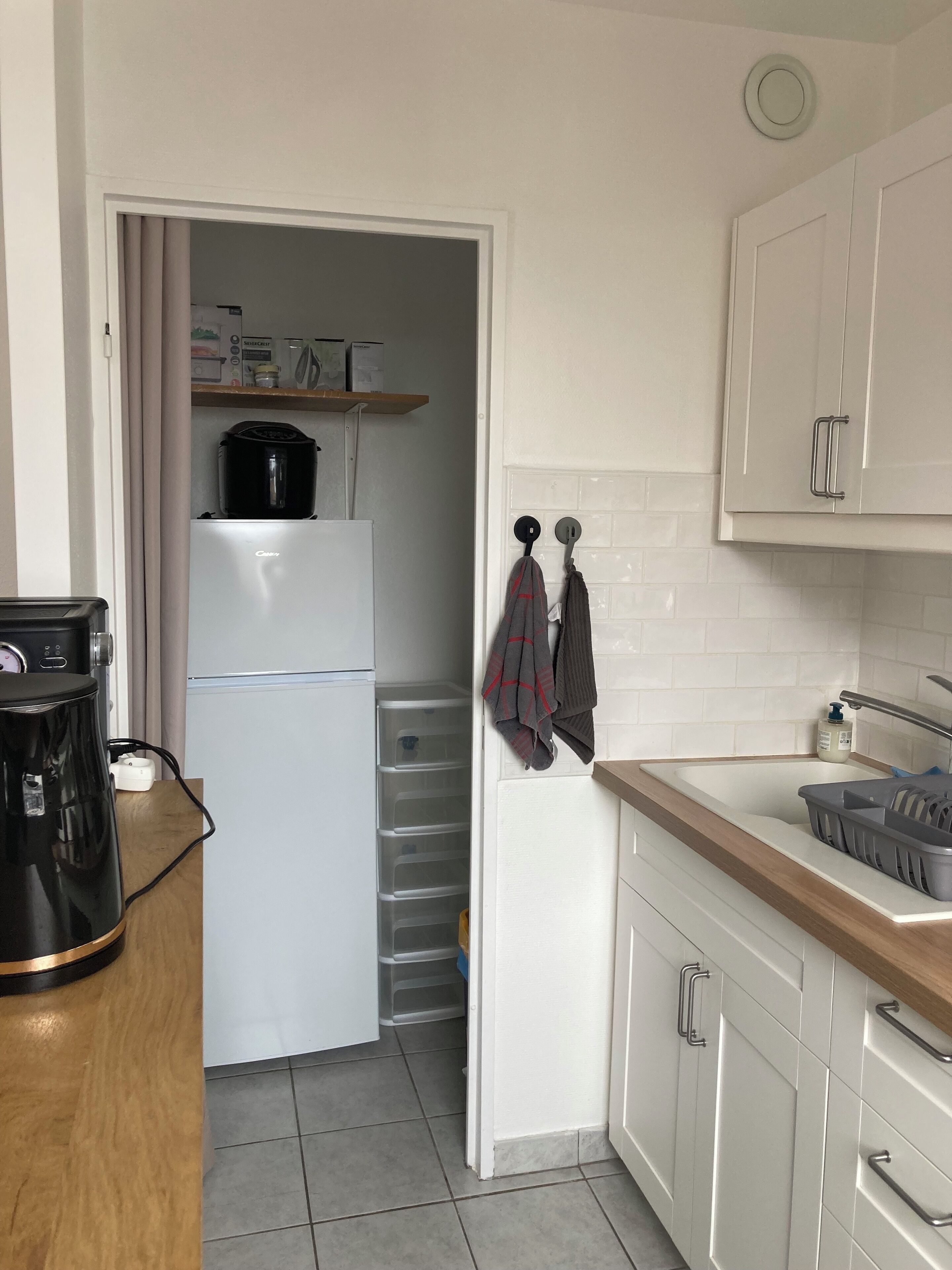 A compact kitchen with a white refrigerator, a coffee maker, and a sink with a soap dispenser.