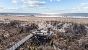 Une terrasse en bois avec deux chaises donnant sur une plage.