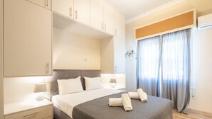 A neatly made bed with a grey quilt, a bedside lamp, and a nightstand with drawers. - Kastella Waves Chic 2-bedroom Getaway w sea View (Piraeus)