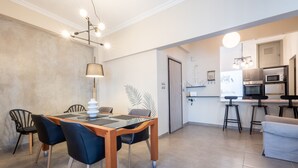 A modern kitchen with a dining area, including a table with chairs, a lamp, and a bar stool. - Kastella Waves Chic 2-bedroom Getaway w sea View (Piraeus)
