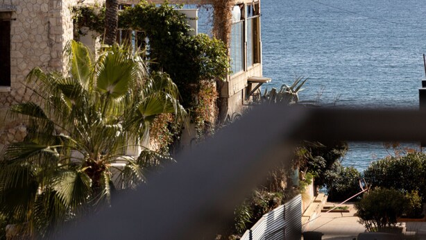 A coastal building with a stone facade, palm trees, and a view of the sea. - Kastella Waves Chic 2-bedroom Getaway w sea View (Piraeus)