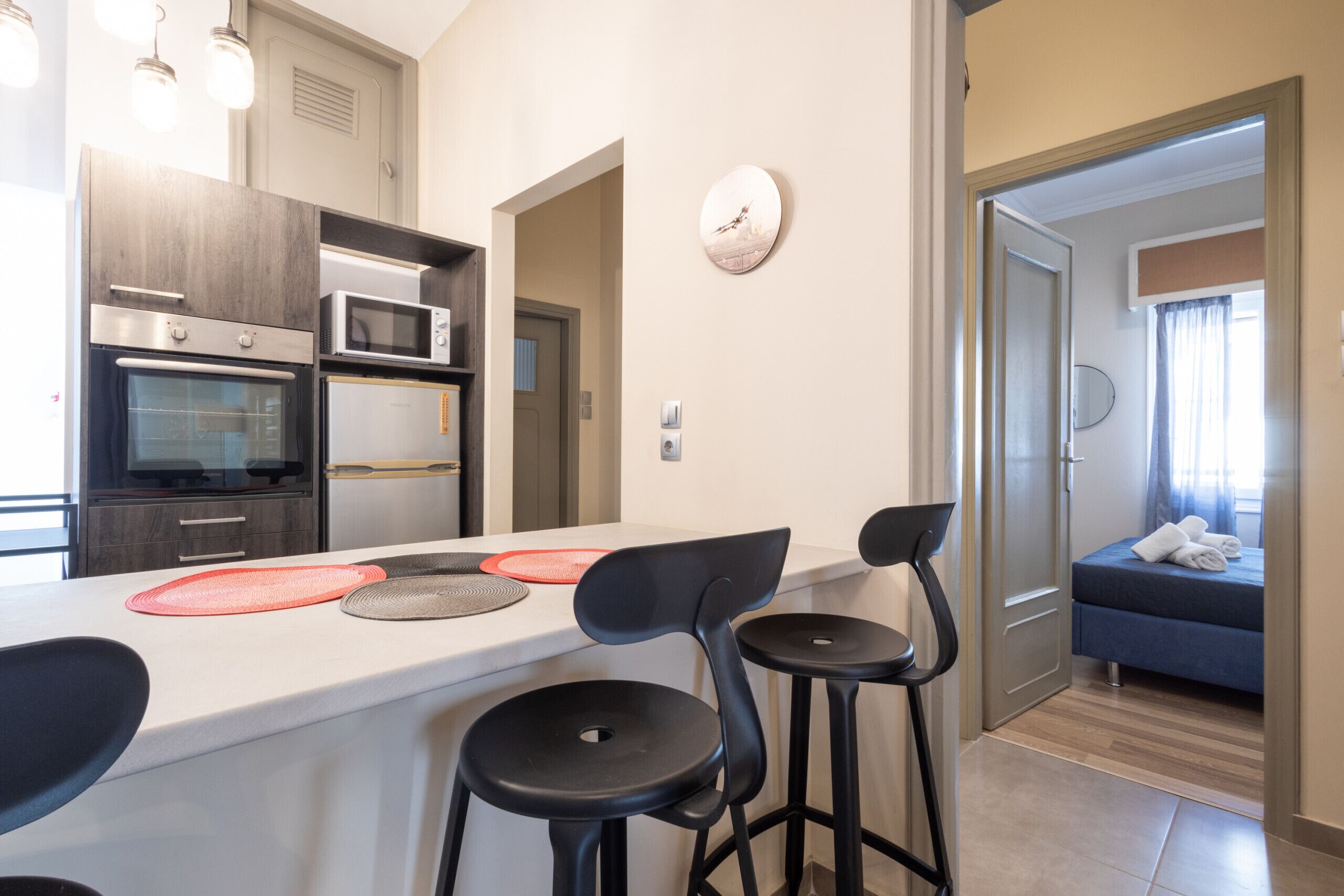 A modern kitchen with a white countertop, black bar stools, and a microwave.