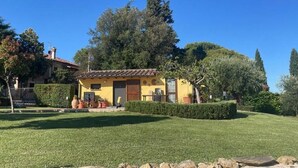 A yellow villa with a tiled roof, surrounded by a well-maintained lawn and hedges. - Trasimeno Holiday Home - Apartment Il Girasole (Castiglione del Lago)
