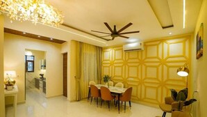 A dining area with a table and chairs, a ceiling fan, and a decorative light fixture. - Premium Service Flats (Kharar)
