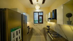 A narrow kitchen with a marble countertop, a built-in stove, and a ceiling light fixture. - Premium Service Flats (Kharar)