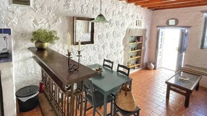 Una cocina rústica con techo de madera, paredes de piedra y suelo de baldosas.