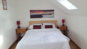 Ein Schlafzimmer mit einem Bett, zwei Nachttischen mit Lampen, einem Gemälde an der Wand und einem Oberlicht.