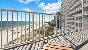 A balcony with a view of a beach and a pool.