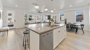 Una cocina amplia con una isla grande, electrodomésticos modernos y un comedor con mesa y sillas.