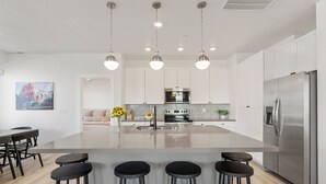 Una cocina moderna con una isla central, electrodomésticos de acero inoxidable y taburetes de bar.