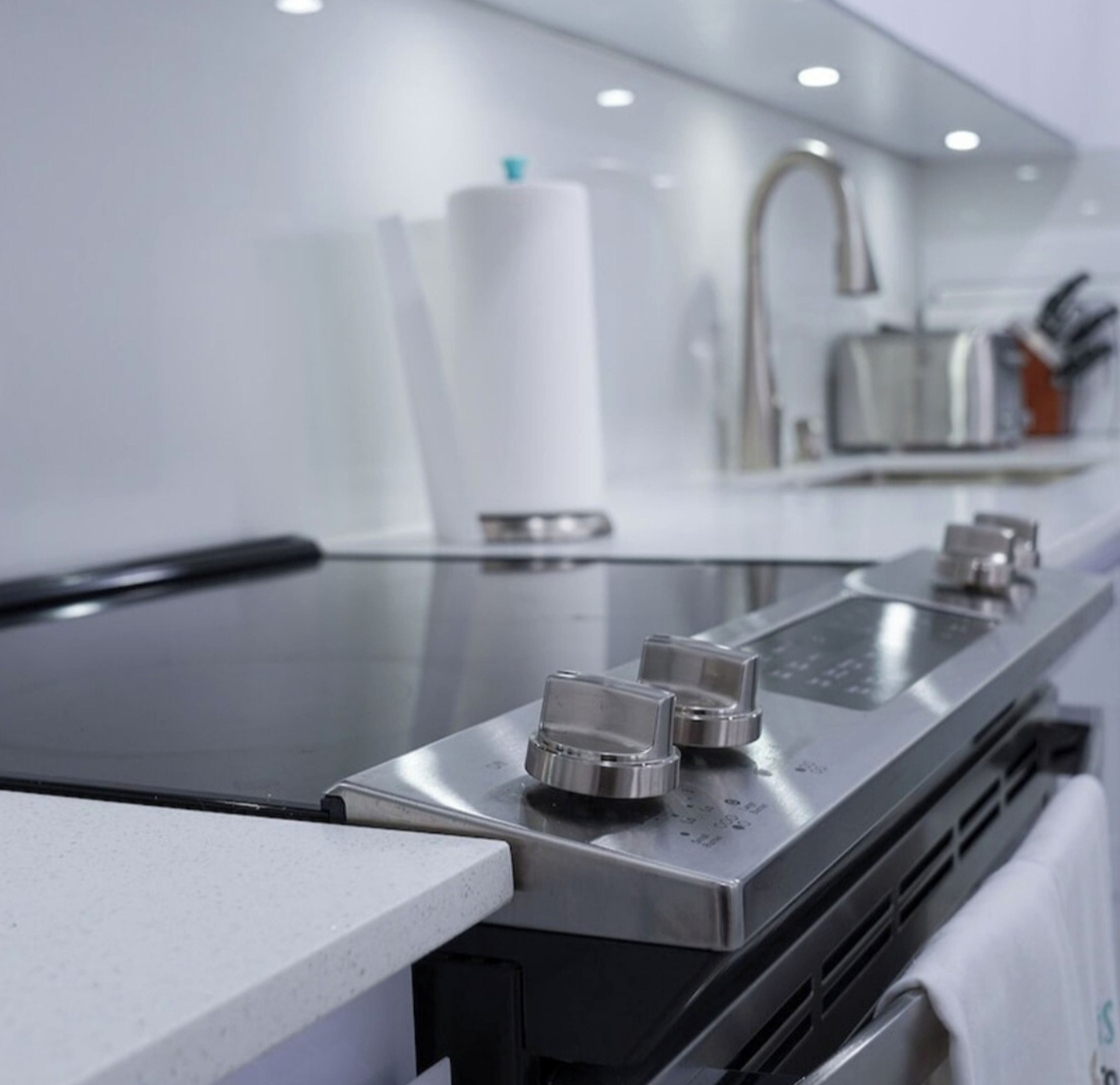 A modern kitchen with a stainless steel countertop, a built-in oven, and a range hood.