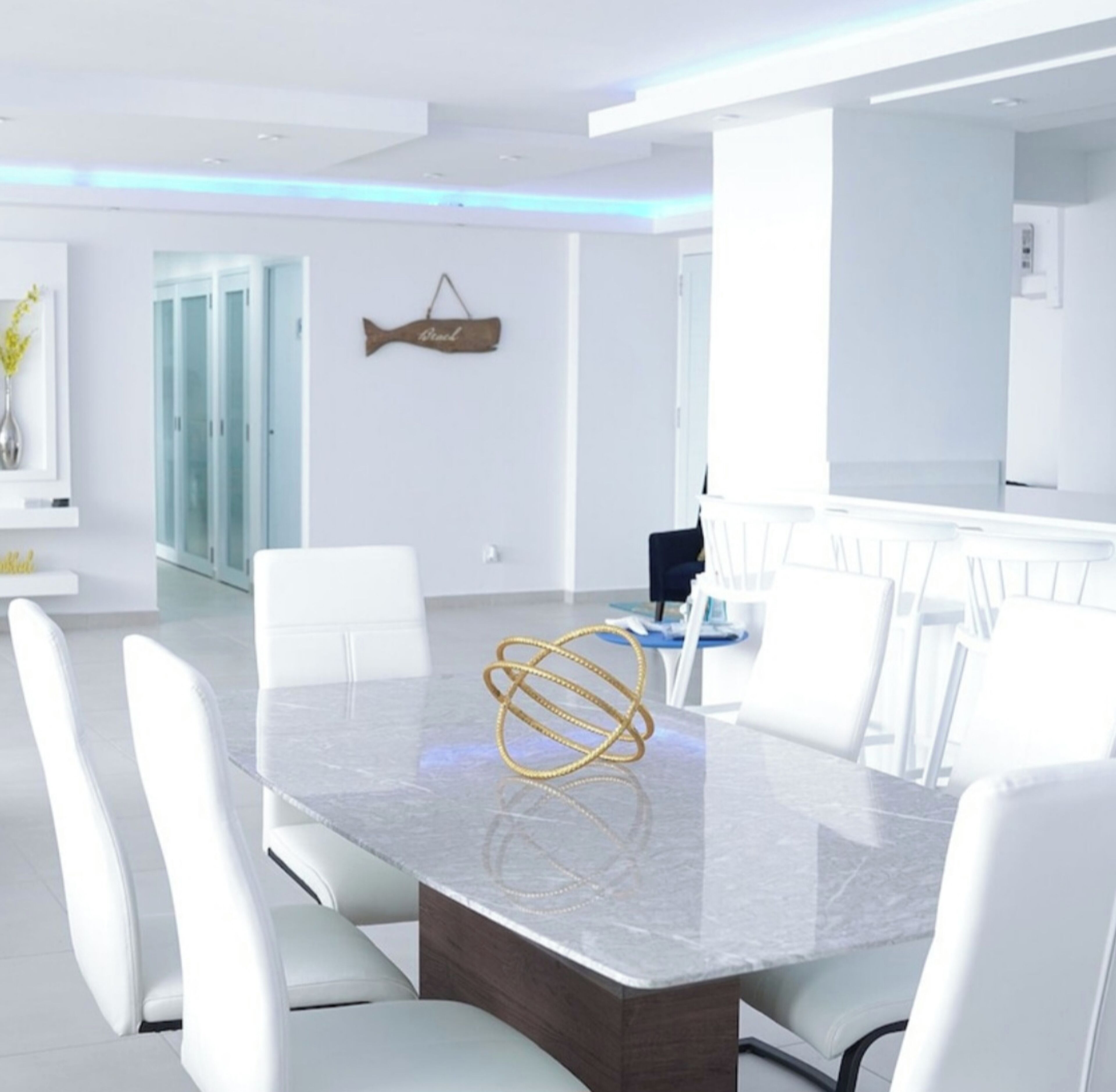 Une salle de conférence moderne avec une table en marbre, des chaises blanches et un élément décoratif mural en forme de poisson.