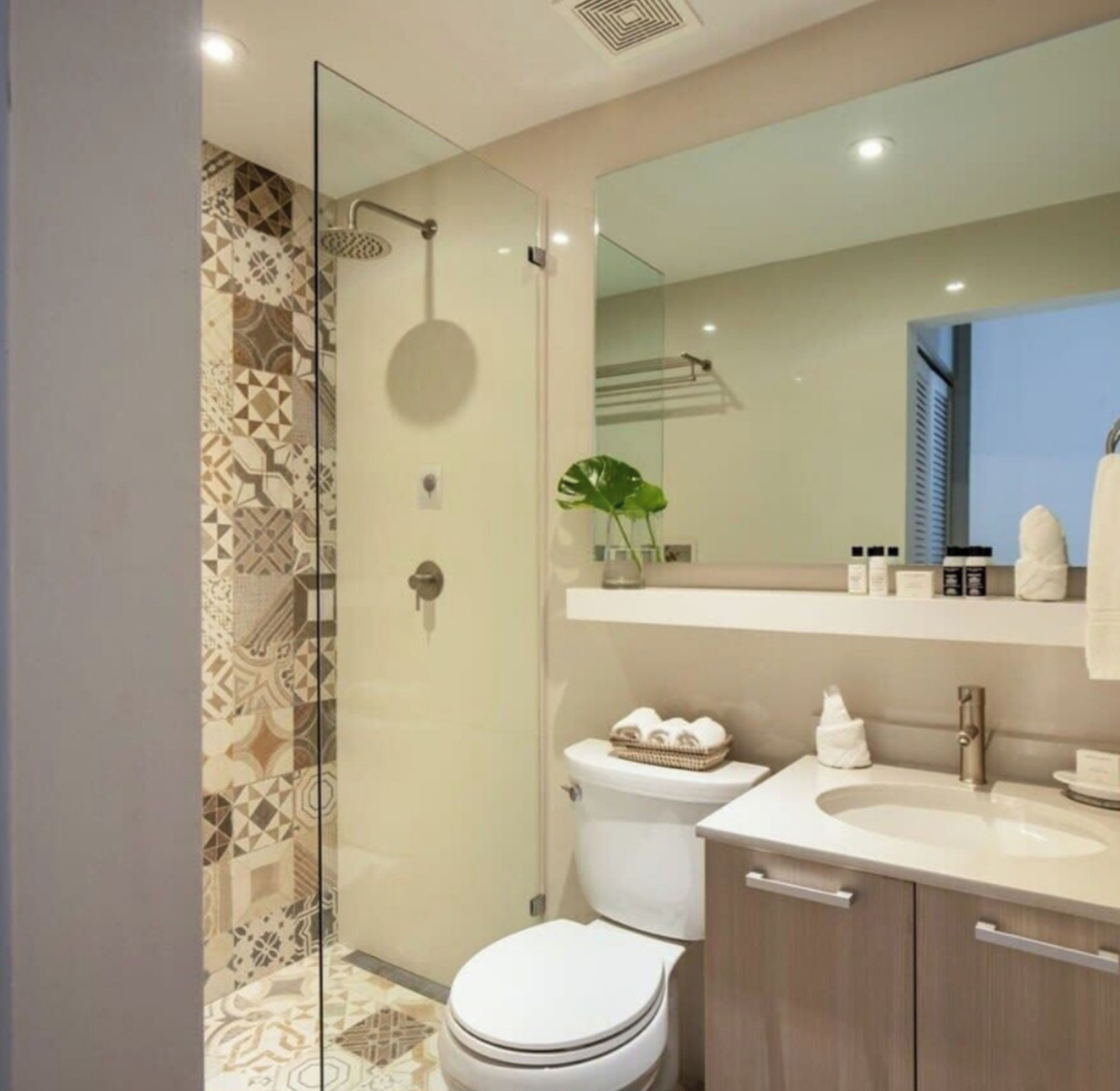 Een moderne badkamer met een douche met glazen wand, een toilet, een wastafel en een badkamermeubel.