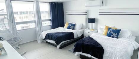Een moderne hotelkamer met twee bedden, een plafondventilator, een bureau en een raam met gordijnen.