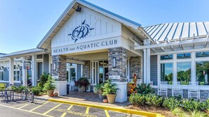 A health and aquatic club with a stone facade, outdoor seating, and a juice box sign.