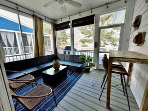 Une véranda abritée avec un espace salon, une table et des chaises.