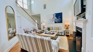 A spacious living room with a staircase, a large mirror, a sofa set, a coffee table, and a fireplace.