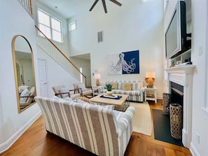 A spacious living room with a staircase, a large mirror, a sofa set, a coffee table, and a fireplace.