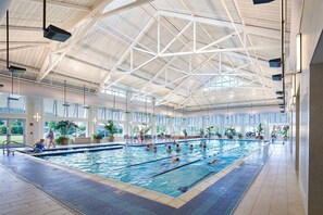 En indendørs swimmingpool med højt til loftet og store vinduer.