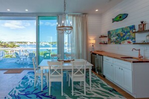 A modern kitchen with white cabinets, a wooden countertop, and a view of the marina through large windows. - Sand Lily - BRAND NEW Three Bedroom Home With Dock On Hope Town Harbour (Hope Town)