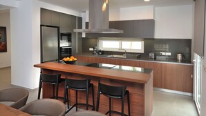 A modern kitchen with a central island, bar stools, and a built-in oven.