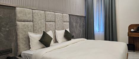 A modern hotel room with a large bed, a bedside telephone, and an air conditioning unit.