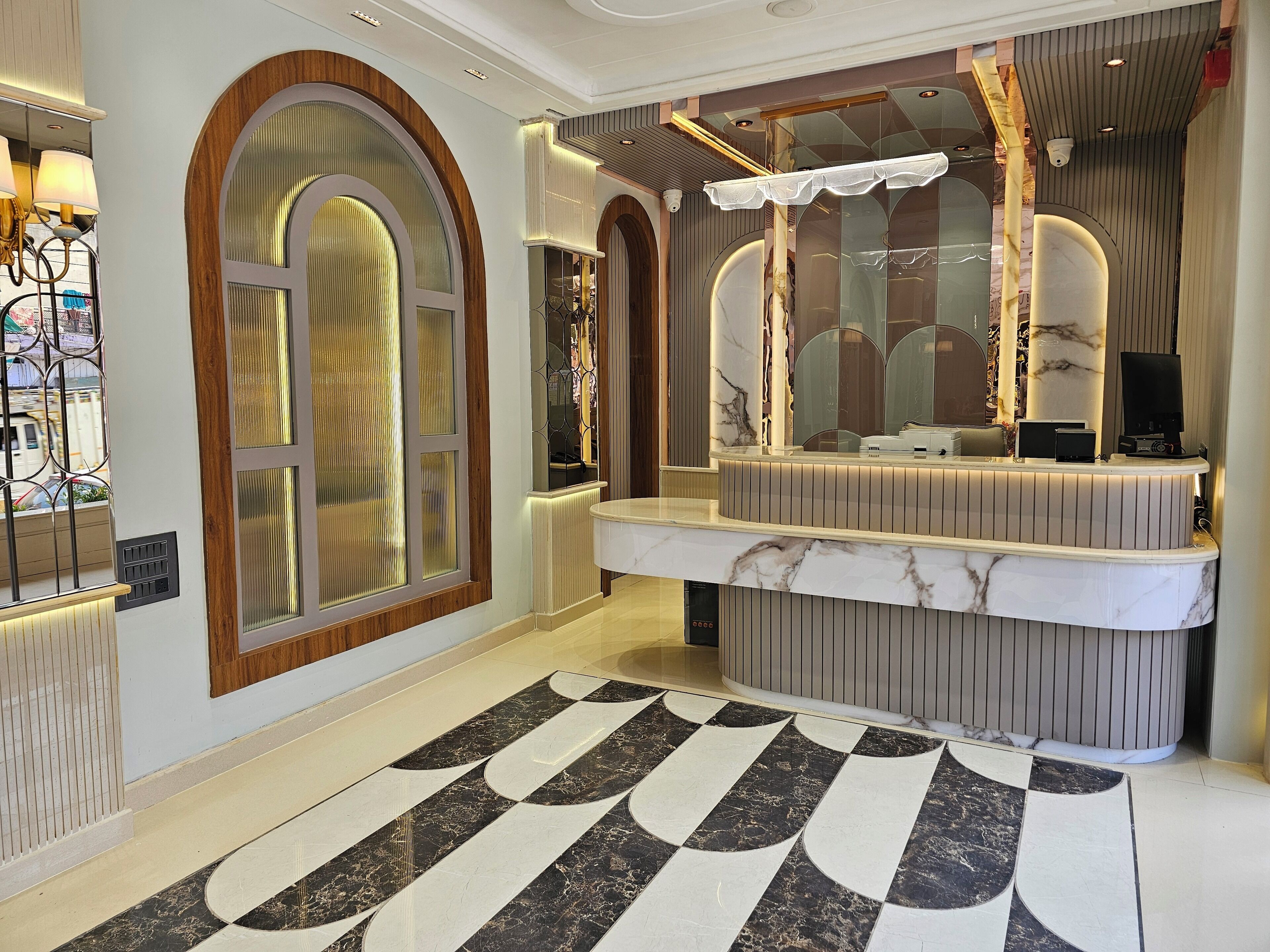 A modern reception area with a marble counter, large arched windows, and a patterned floor.