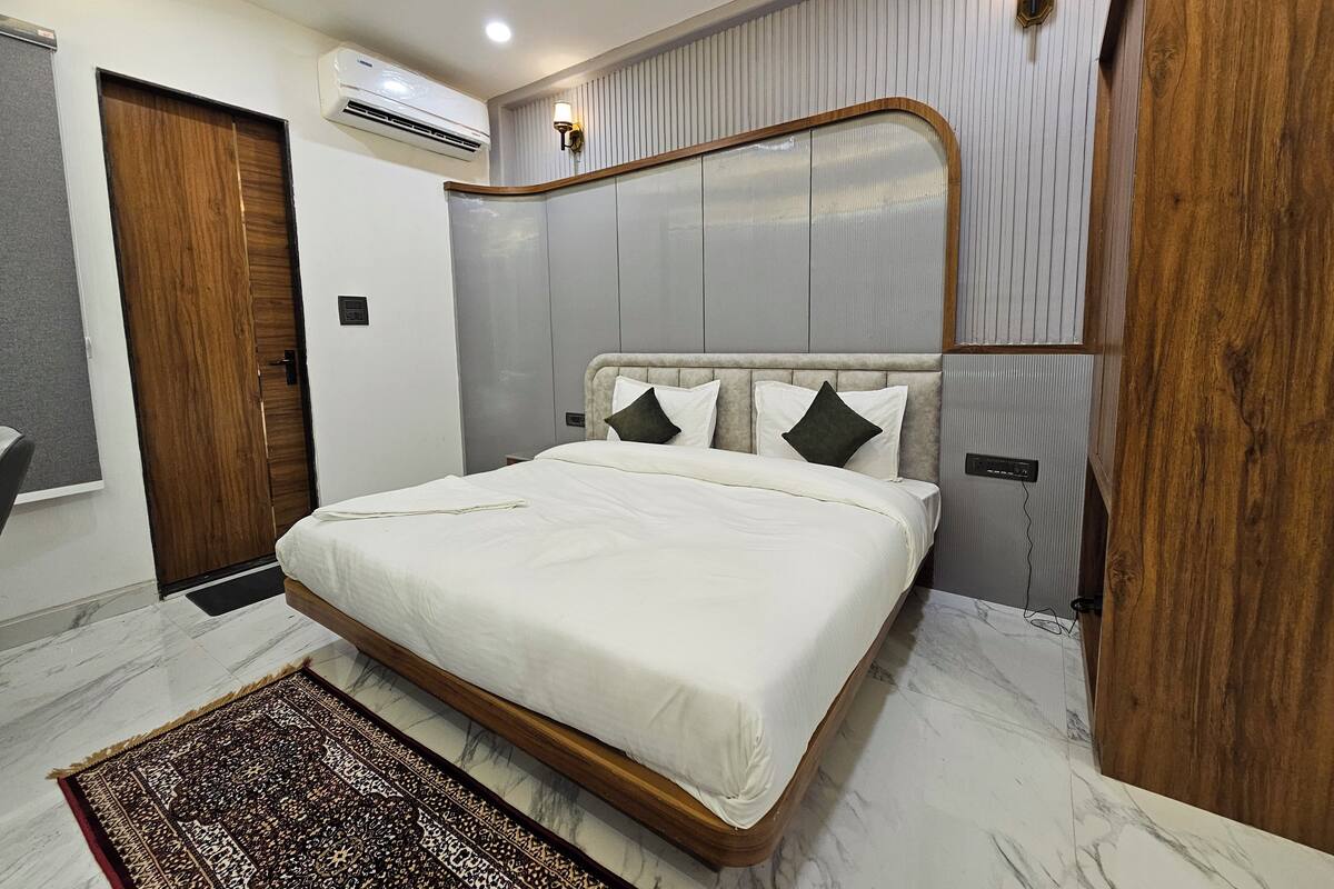 Un dormitorio con cama, ventilador de techo, equipo de aire acondicionado y alfombra estampada.