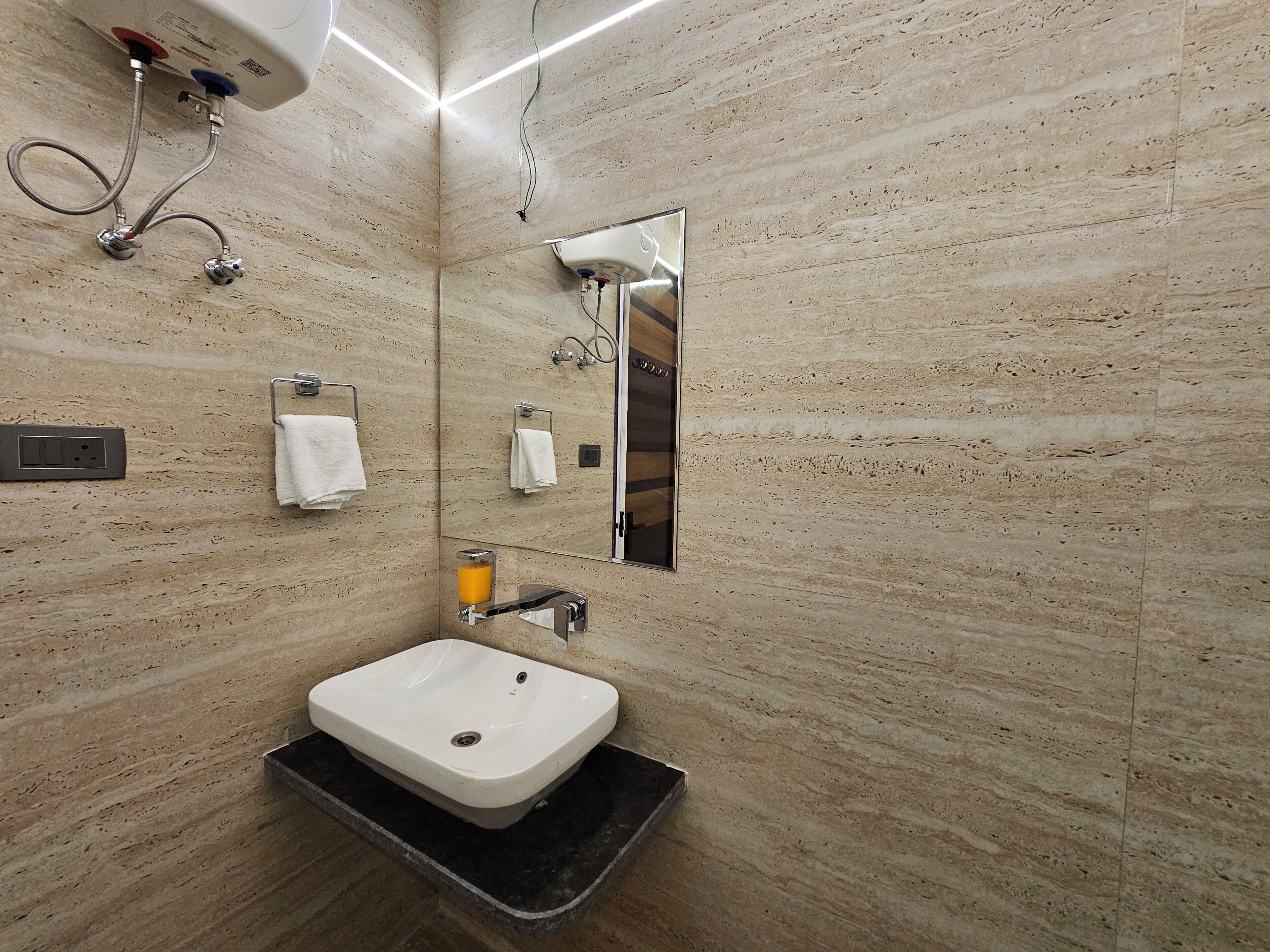 A modern bathroom with a white sink, a mirror, and a towel rack.