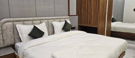A neatly made bed with white bedding and a wooden headboard, a wooden wardrobe, and a mirror on the wall.